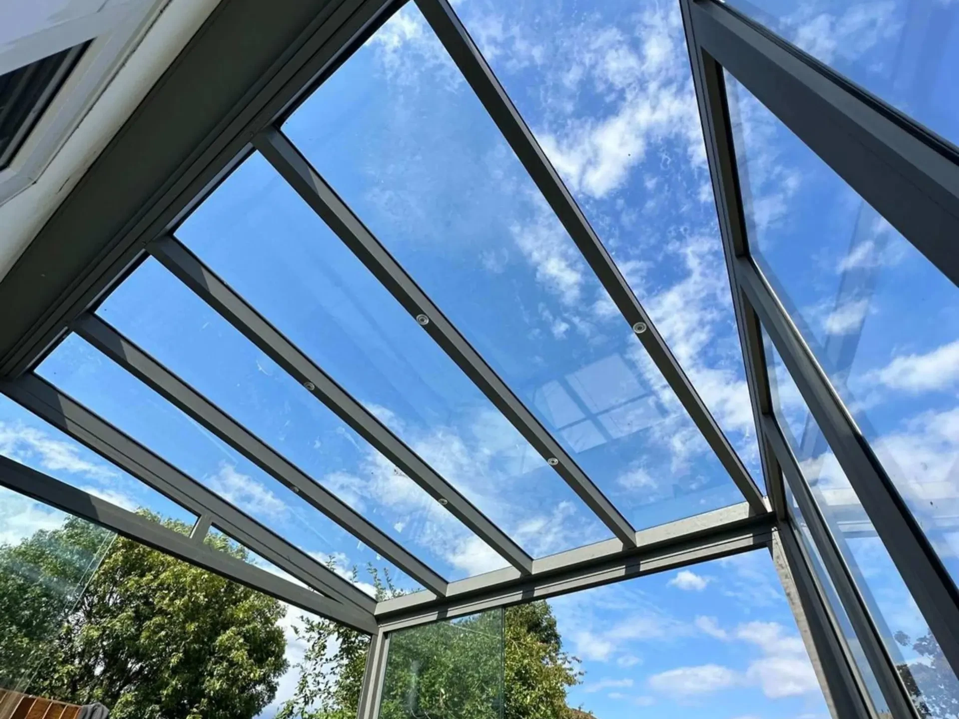 Anthracite grey frame glass room veranda with glass sliding doors, safety glass roof and LED spot lights.