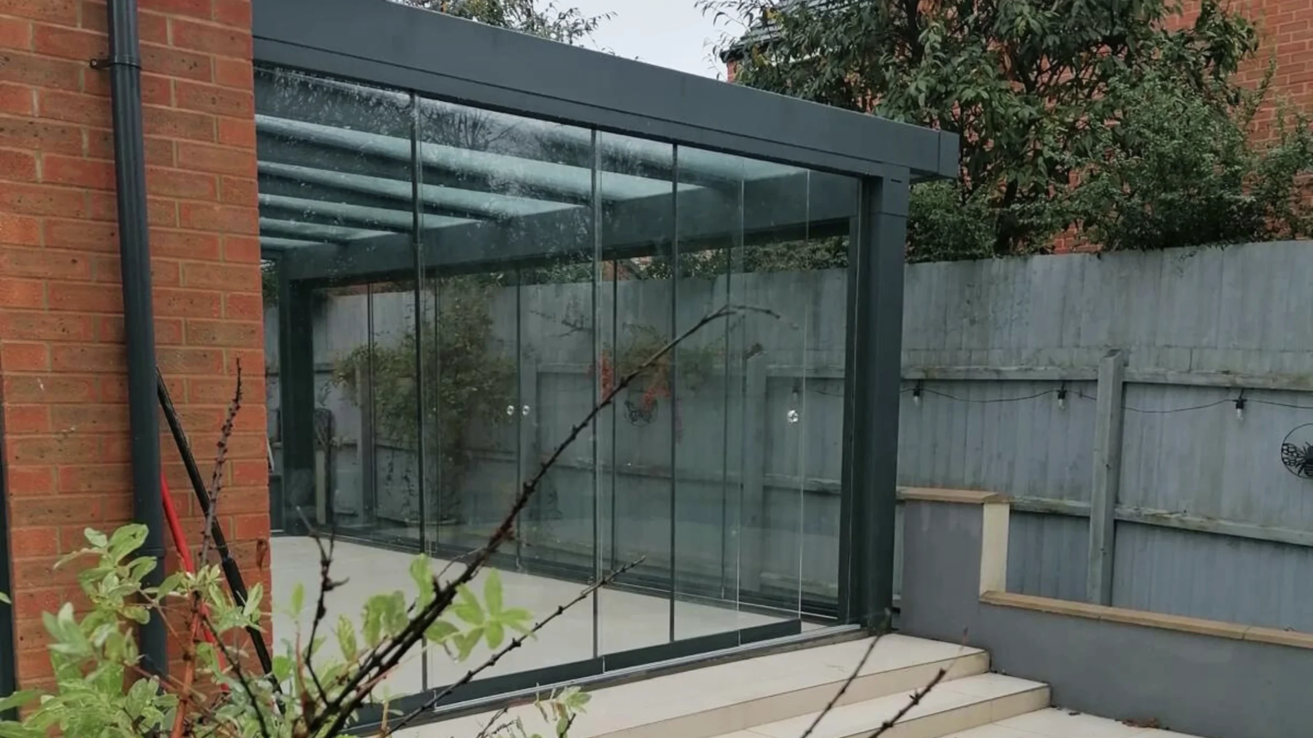 Anthracite grey glass room veranda with glass roof and sliding doors.