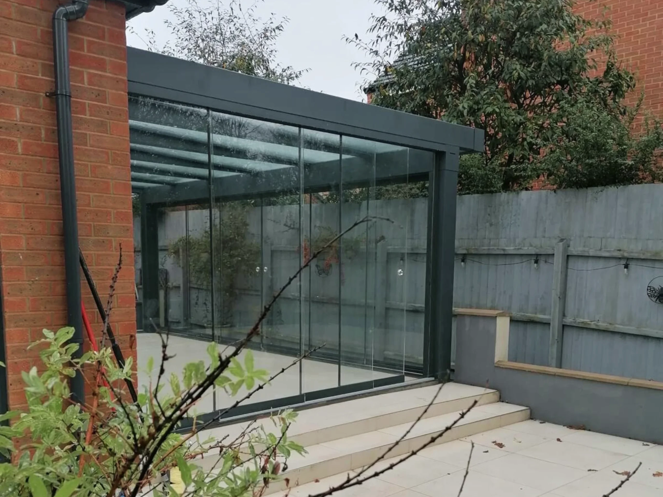 Anthracite grey glass room veranda with glass roof and sliding doors.