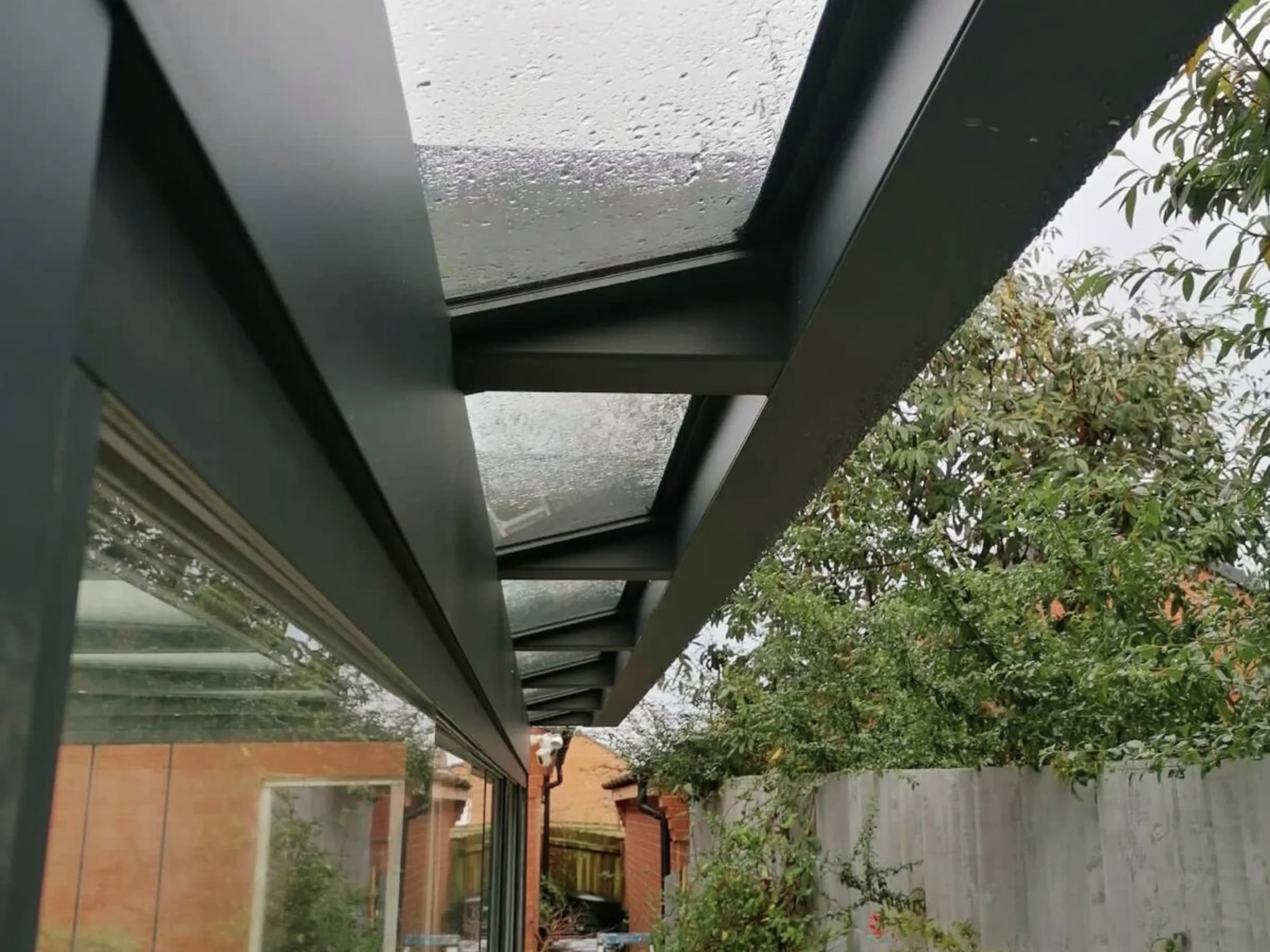 Front profile of Anthracite grey glass room veranda with glass roof and sliding doors.