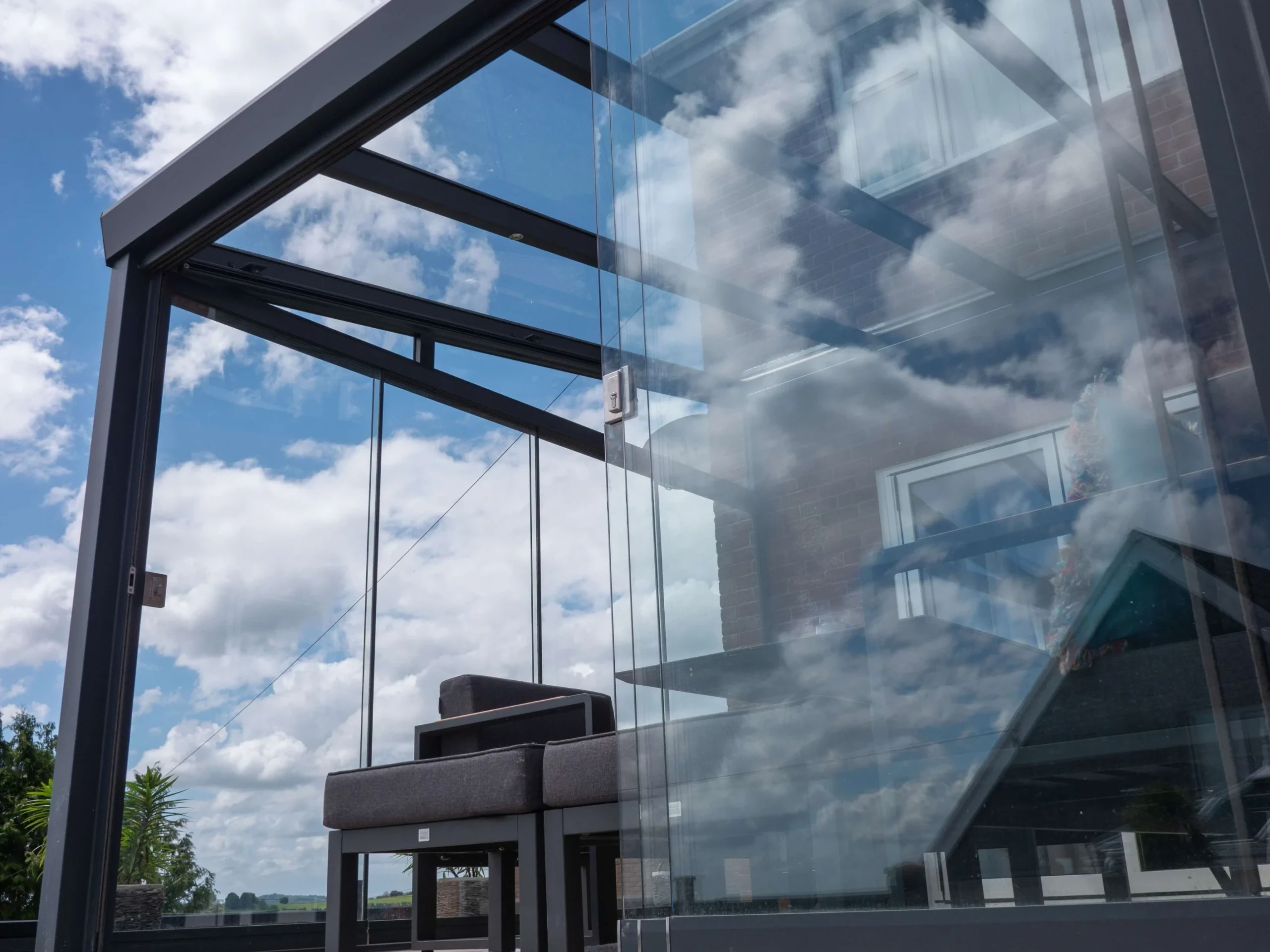 Anthracite grey aluminium framed glass room veranda with lockable glass sliding doors on 2 openings.