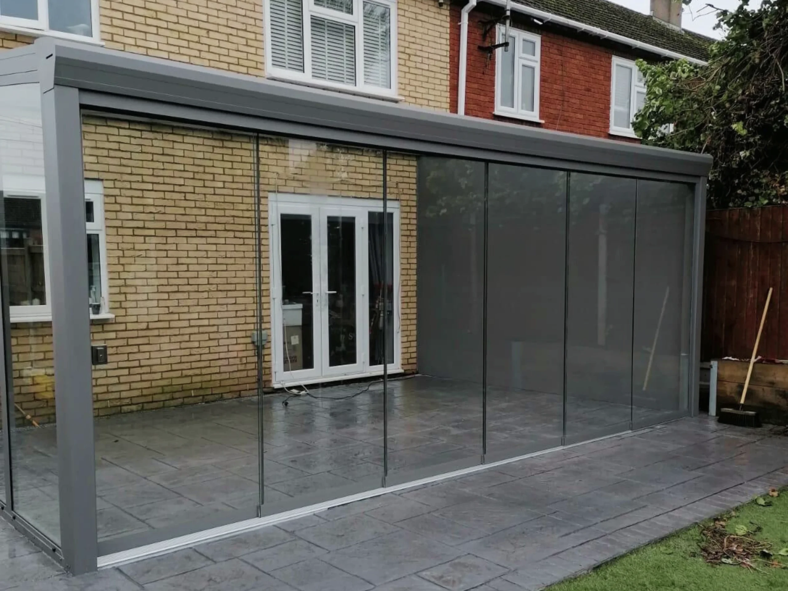 Anthracite grey glass room veranda with a glass roof, glass sliding doors and grey aluminium wall.