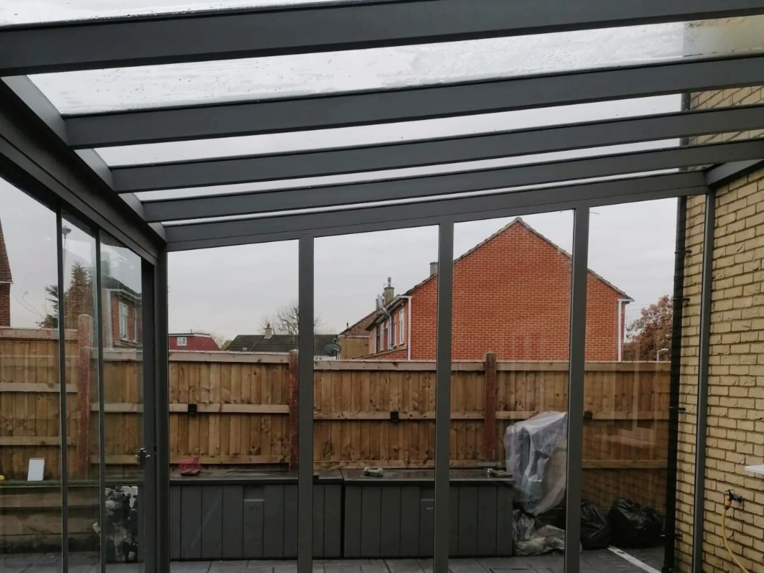 Anthracite grey glass room veranda with a glass roof, glass sliding doors and grey aluminium wall.