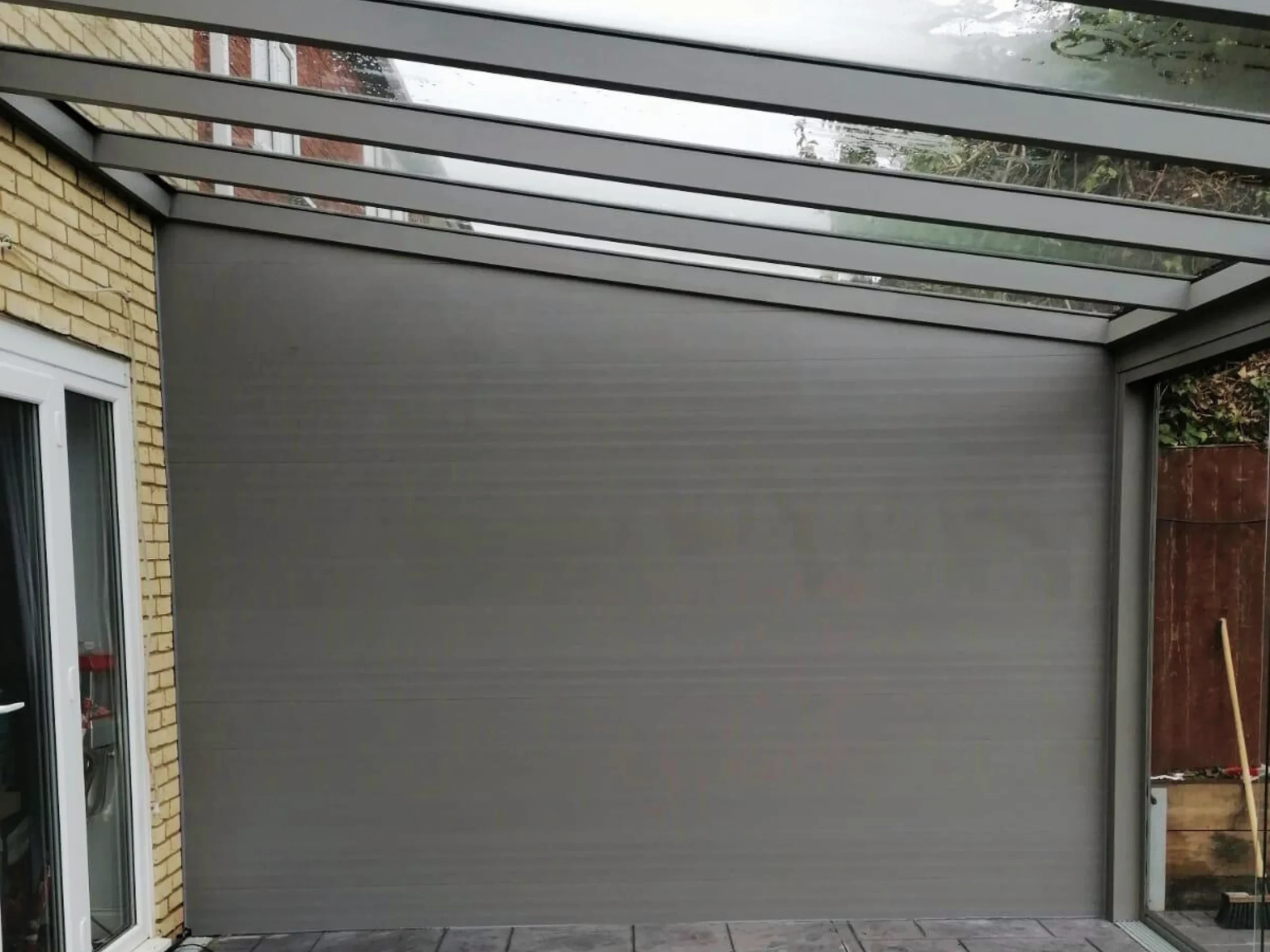 Anthracite grey glass room veranda with a glass roof, glass sliding doors and grey aluminium wall.