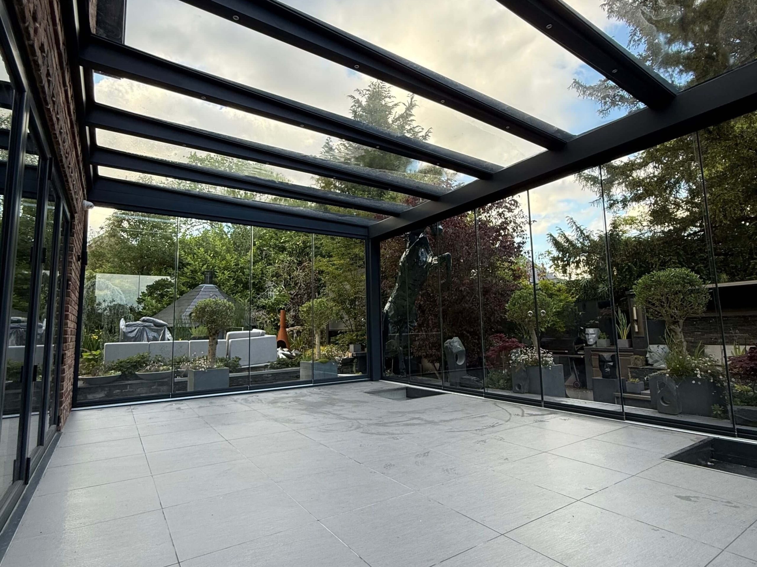 Anthracite grey glass room veranda with clear glass roof, sliding doors and spot lights.