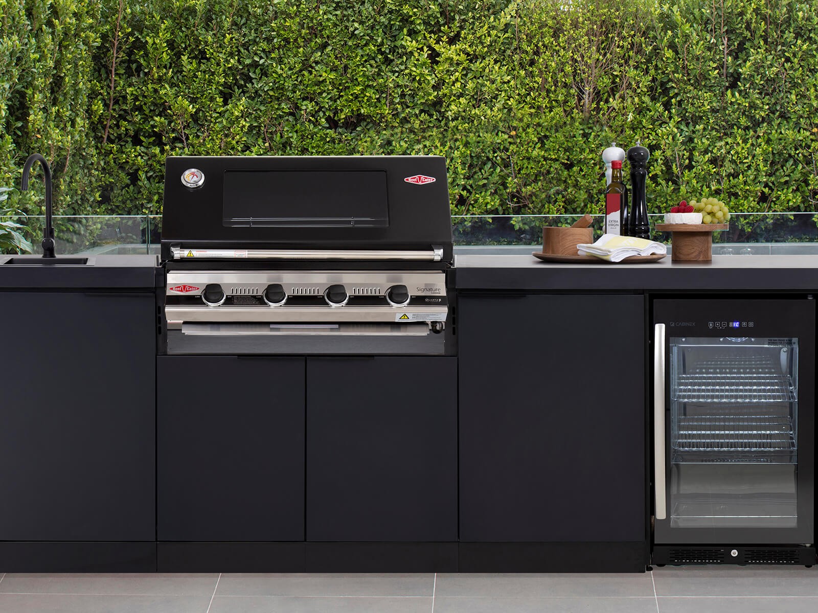 Dark grey outdoor kitchen cabinet, with black and chrome steel grill and fridge
