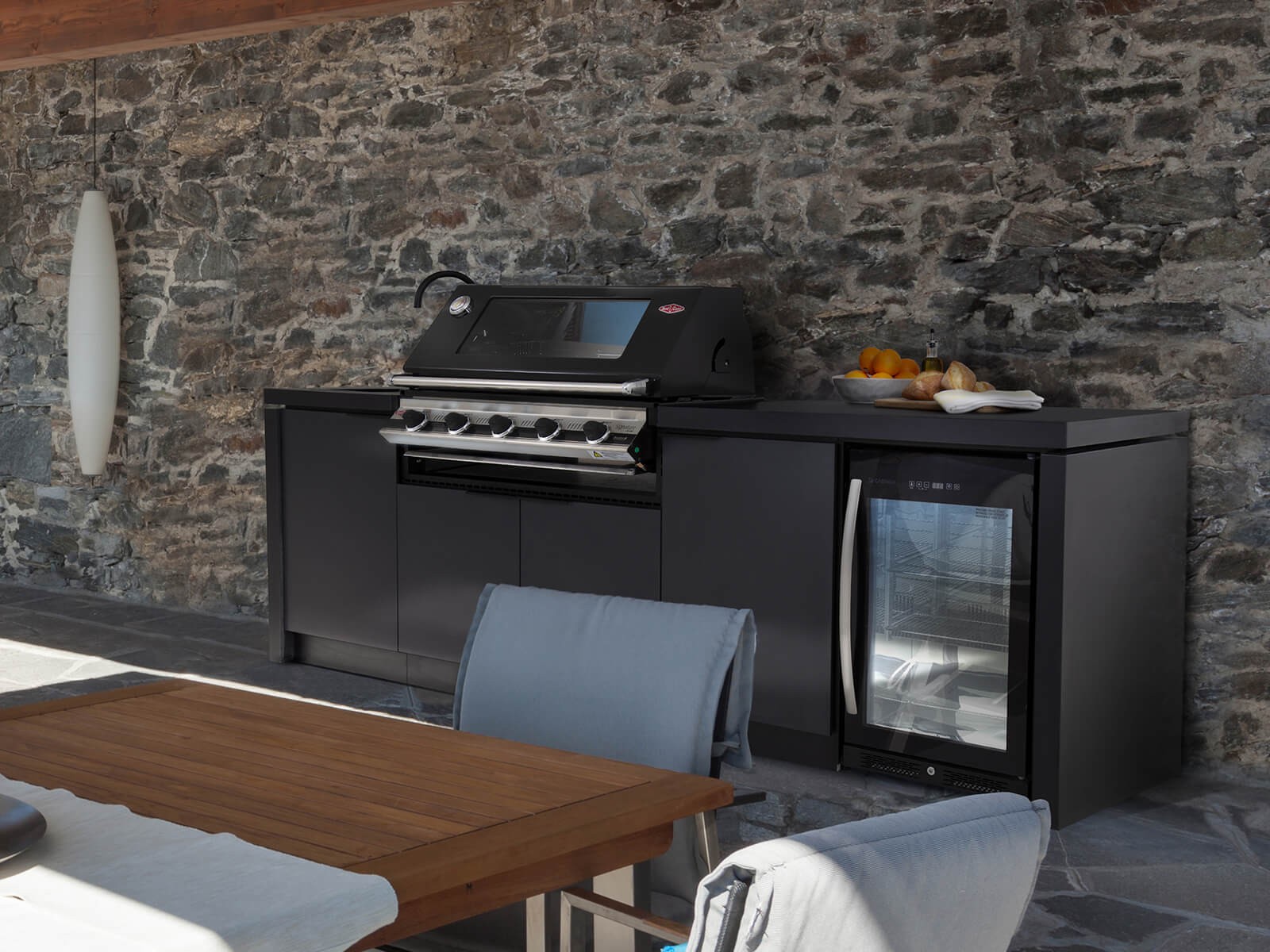 Black composite outdoor kitchen unit with a black and chrome grill, tap and fridge.