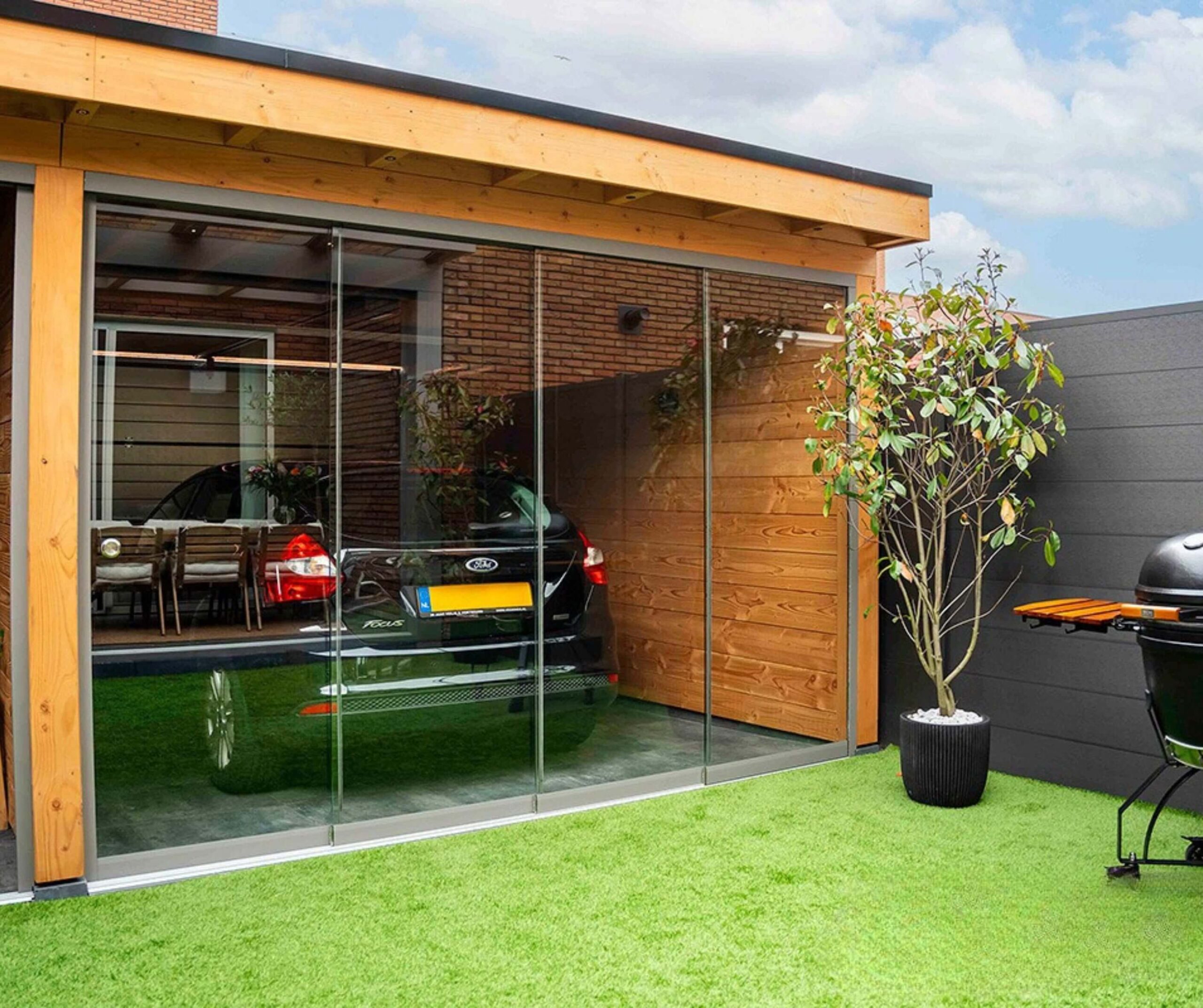 Single enclosed carport with grey aluminium framed glass sliding doors, sheltering a black hatchback car.