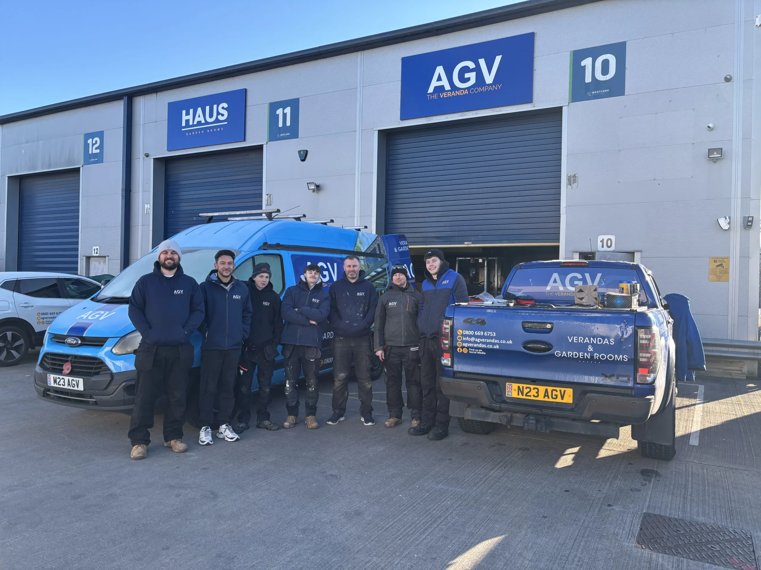 AGVerandas Ltd members of staff at the front of the showroom entrance, with a baby blue company van and a dark blue company 4x4 truck.