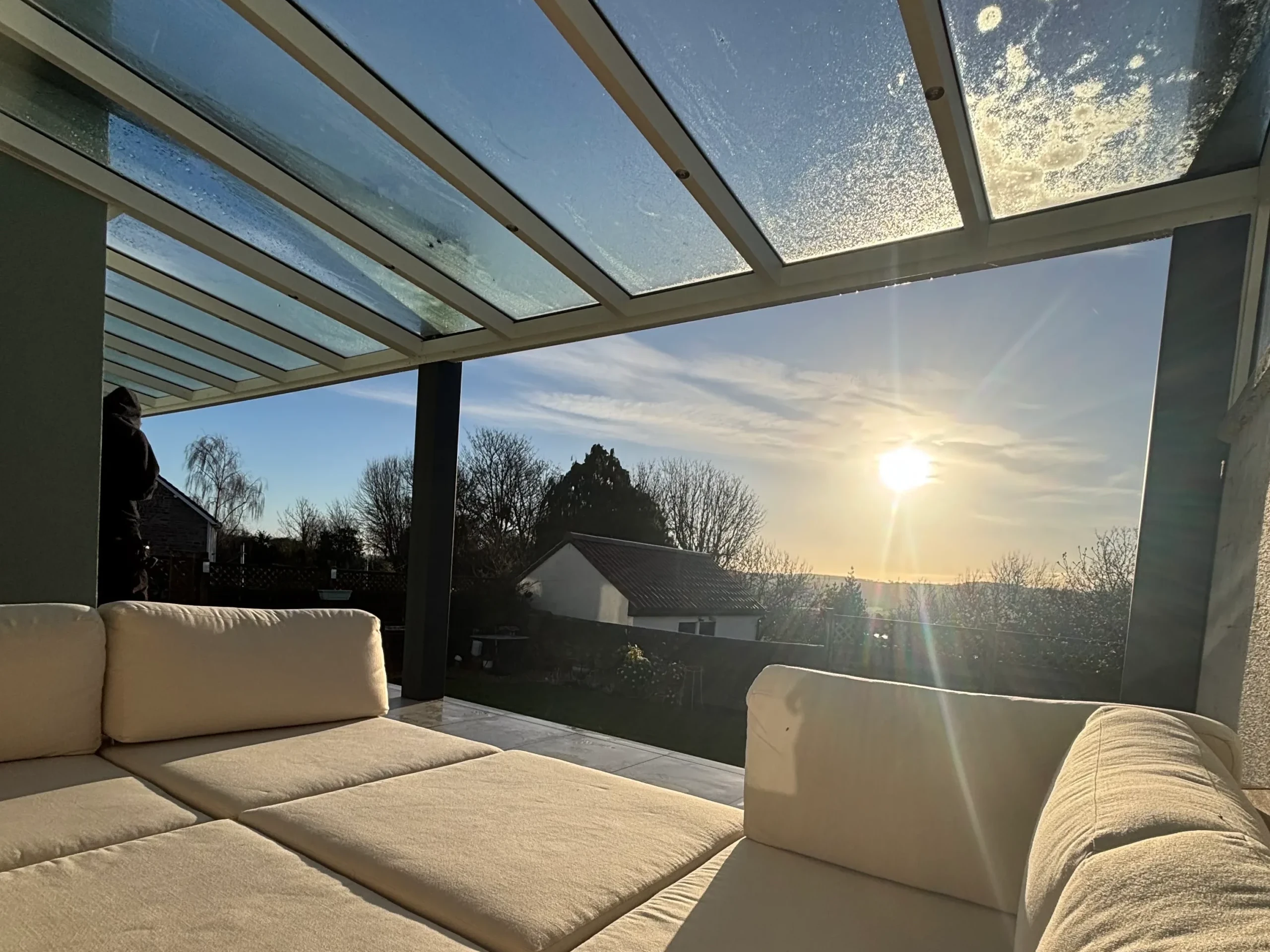 Cream garden sofa under an off white and anthracite grey aluminium framed glass roof veranda with LED spot lights.