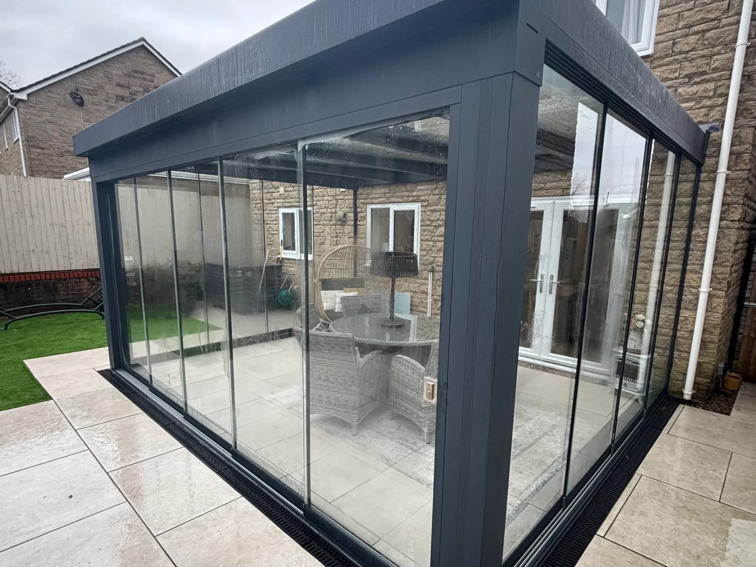 Anthracite grey aluminium framed glass room veranda with closed lockable glass sliding doors.